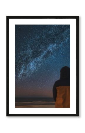 A silhouette of a person in front of a universe constellation. Concept of outdoors night skies and Milky Way observation.