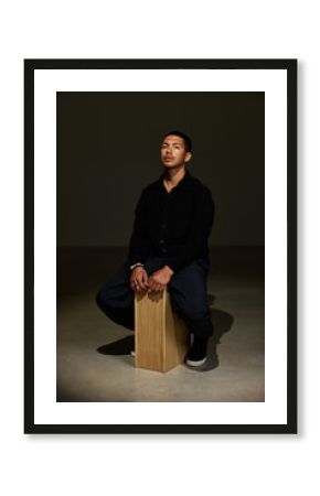 Man sitting on wooden box in dimly lit space