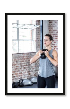 Focused woman lifting kettlebell in gym, building strength and endurance, copy space