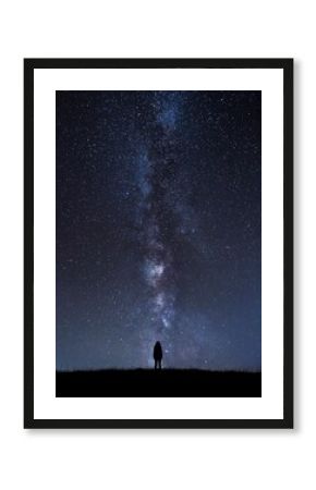 Silhouette of unrecognizable person standing under cosmic sky at night