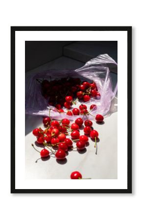 Juicy red cherries tumble out of a plastic bag, brightening up a sunlit kitchen space