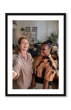 Two women smile for a casual selfie in a bright office space