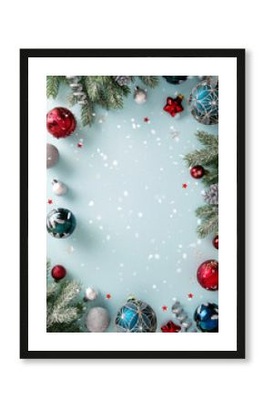 Vertical bright light blue Christmas background with a decorative border of snowy fir branches, swirling ribbons, and vibrant red, silver, and patterned teal baubles
