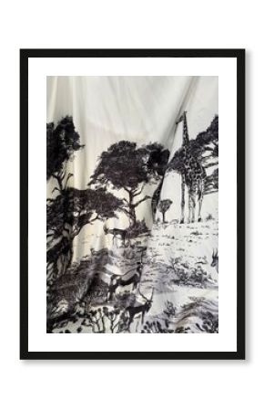 A close-up of fabric with a detailed black and white safari pattern featuring a giraffe, antelope, and trees. The image is ideal for classic style illustrations, apparel prints and decorative elements