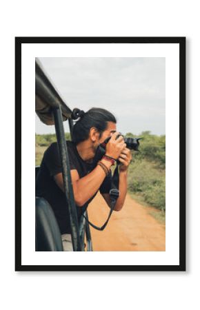 Happy traveling male with professional photo camera taking photos of wildlife during safari