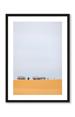 People exploring a desert landscape with two parked safari vehicles under a vast sky. Phuoc Dinh, Ninh Thuan, Vietnam