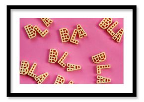 Close-up view of alphabet pasta letters forming words ‘bla’ against pink background  