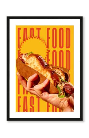 Hand holding delicious hot dog sandwich with grilled sausage, salad and bun on bold yellow background with fast food typography. Conceptual design. Concept of food, pop art, poster, ad