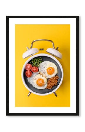 Breakfast of fried eggs with bacon or sausage and vegetables. ? plate on a vintage alarm clock