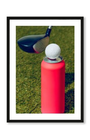 Golf club aiming at ball on blank pink can for mockup standing on grass. Concept of sports branding, beverage campaigns, premium leisure lifestyle, and product advertising mockups.