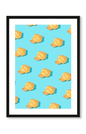 Creative pattern made of freshly baked croissant on pastel blue. Minimal homemade pastry background.