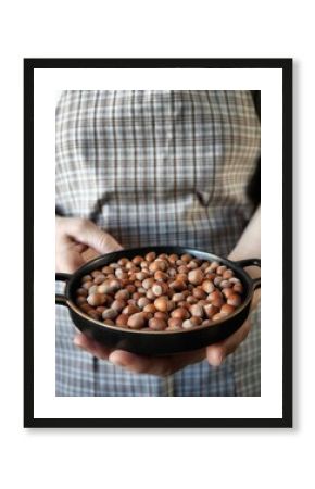 Hazelnuts in retro plate. Woman holding Nuts in hands. Vertical photo can used web banner poster and menu cover 