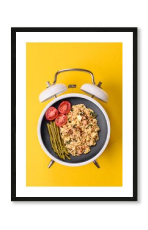 Breakfast of fried eggs with bacon or sausage and vegetables. ? plate on a vintage alarm clock