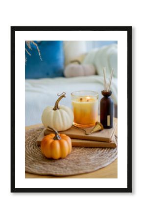 Home autumn decor in warm shades. Pumpkin, candle, dried flowers, pillows.