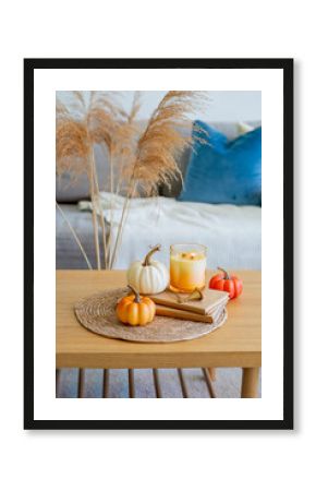 Home autumn decor in warm shades. Pumpkin, candle, dried flowers, pillows.