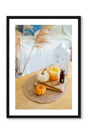 Home autumn decor in warm shades. Pumpkin, candle, dried flowers, pillows.