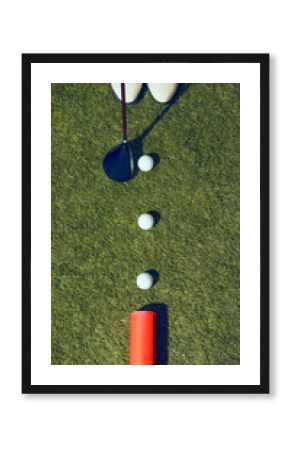 Top view of golf balls lined with club and pink mockup can on green grass. Concept of sports lifestyle, beverage advertising, premium branding, and editorial creative design.