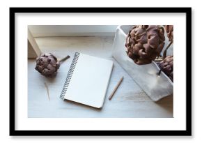 composition with a notebook and dried artichokes on a white old surface