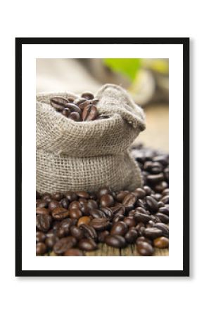 Black roasted coffee beans in a small burlap sack