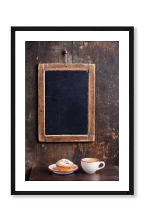 Coffee cup and vintage slate chalk board hanging on wooden backg