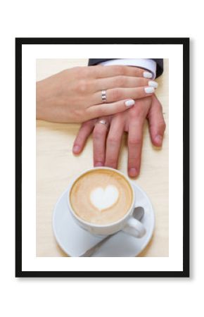 Women's and men's hands with wedding rings with cup of coffee