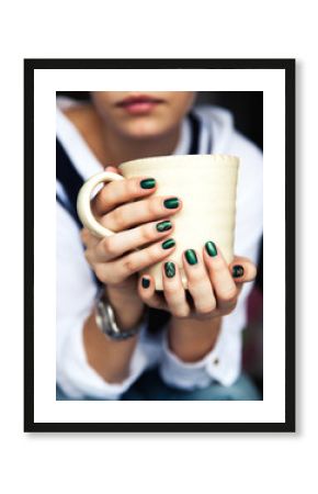 Stylish fashionable girl with a Cup of coffee and a green manicure in jeans. Fashion, care, beauty