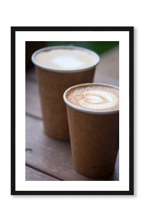 Two cups of latte art with heart shape in brown paper cup. selective focus