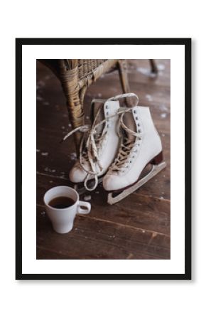 A pair of ice skates with cup of tea standing on the floor