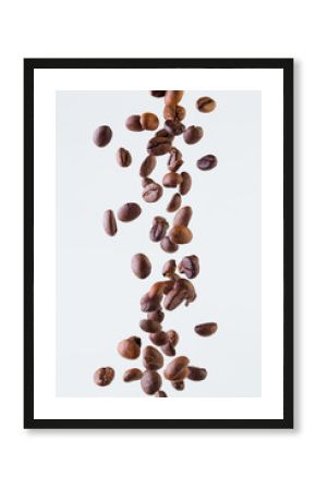 Falling grains of roasted coffee on a white background