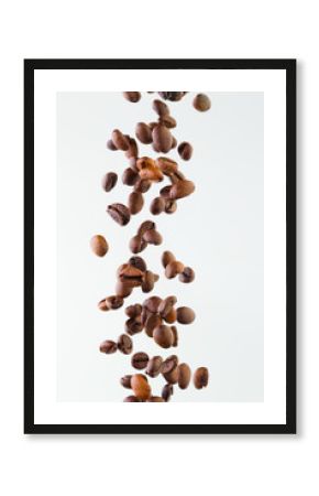 Falling grains of roasted coffee on a white background