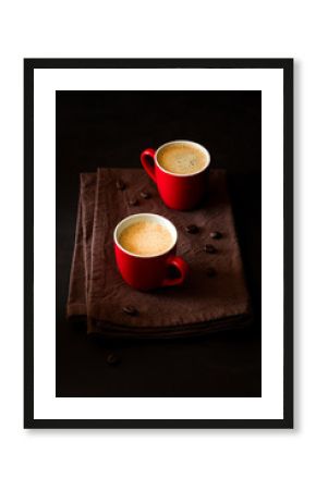 Two red cups of espresso on dark wooden background decorated coffee beans
