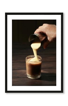 Woman adding condensed milk to coffee at table