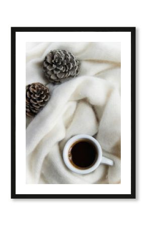 Top view of coffee cup in a cozy warm blanket with pine cones. Autumn-winter concept
