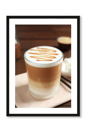 Glass with delicious caramel latte on table