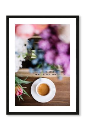 Delicious freshly brewed morning espresso coffee with a beautiful crema standing on the rustic wooden table with blowers blurred on the foreground, top view, flat lay