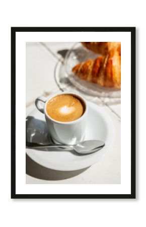 Hot coffee and croissant breakfast in a sunny morning, natural light.