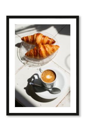 Hot coffee and croissant breakfast in a sunny morning, natural light.