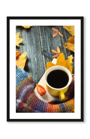 Autumn comfort. Mug of hot coffee with a colorful scarf with colorful autumn leaves on wooden background copy space
