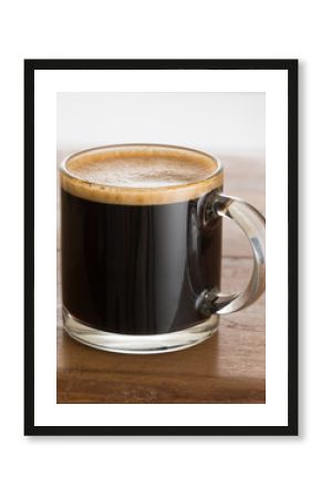 Black coffee and froth in glass mug wood table