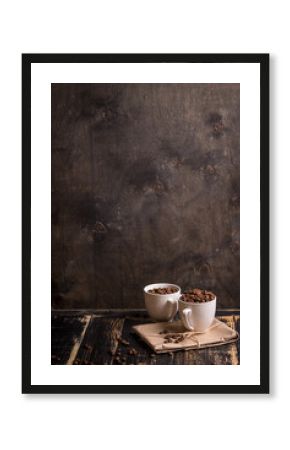 Cup with coffee beans at dark wooden background