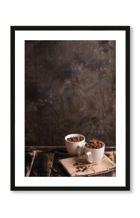 Cup with coffee beans at dark wooden background