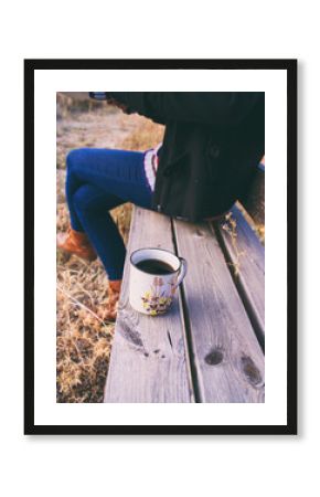 Mujer sentada en un banco en un parque en otoño con su taza de café