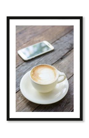 Hot coffee and smartphone on a wooden table.