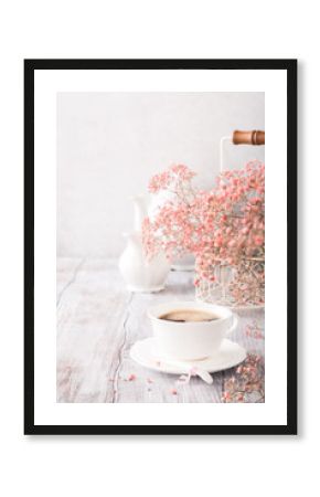 White cup of coffee with pink flowers on old white wooden background with copy space.