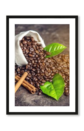 Pile of coffee beans and green leaves in bag on dark background