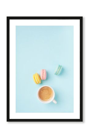 Cup of coffee and colorful macaron on pastel blue background top view. Cozy morning breakfast. Fashion flat lay style. Sweet macaroons.