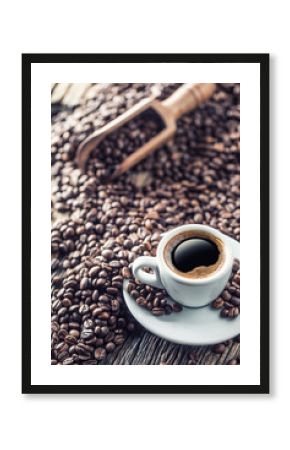 Cup of black coffee with beans on wooden table