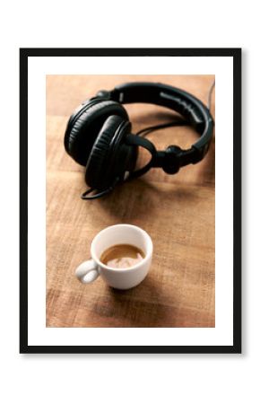 Black headphones and a cup of coffee on rustic wooden background. Copy space. 