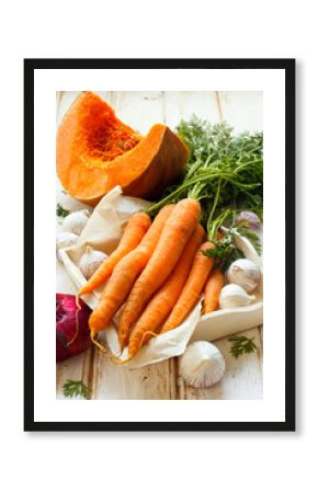 Pumpkin, carrot, garlic and red onion on white wooden background