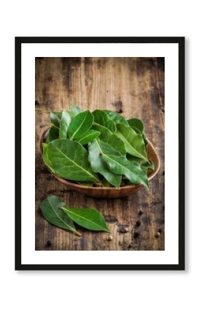 Fresh bay leaves in a wooden bowl on a wooden background